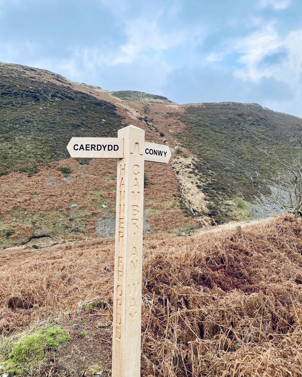 A wooden Cambrian Way signpost pointing to Caerdydd and Conwy