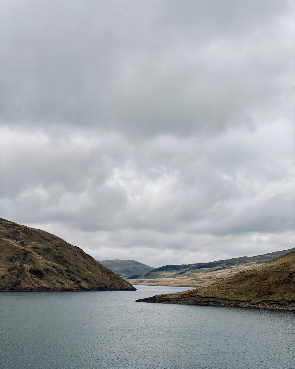 A lake between steep hillsides under a cloudy sky