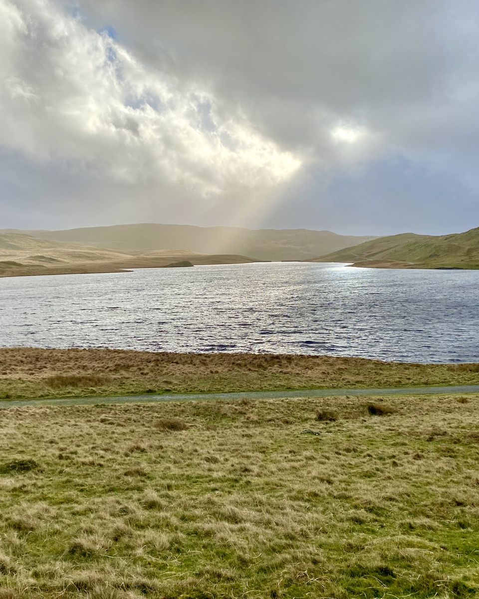 Sunlight breaking through cloud over a lake in the hills