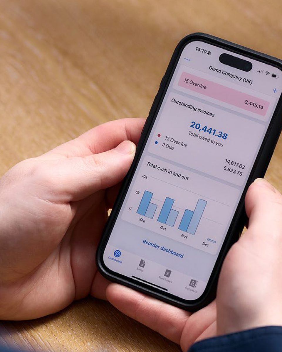 The Xero app on a phone, showing outstanding invoices and cash in and out